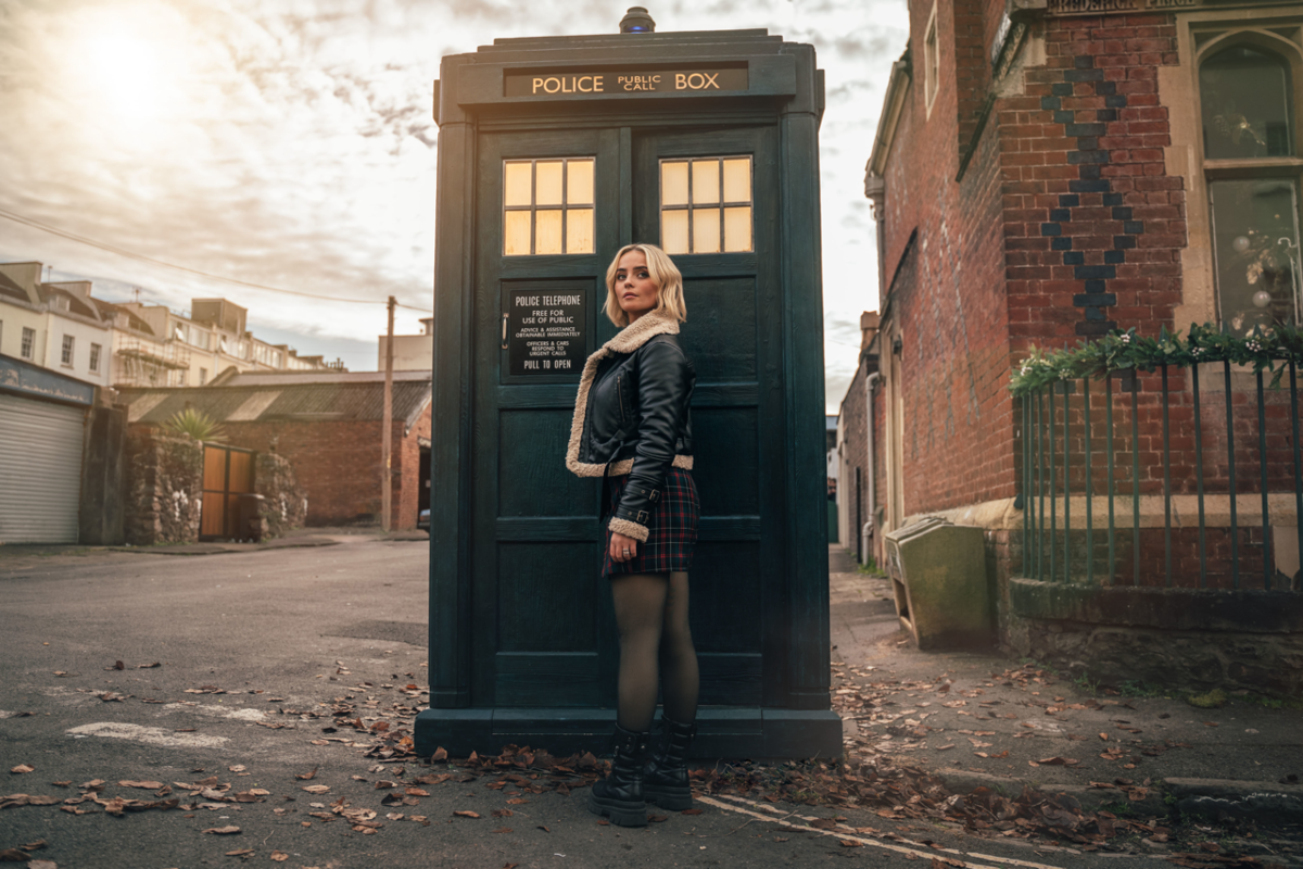 Ruby Sunday stands in front of the TARDIS in an ordinary street